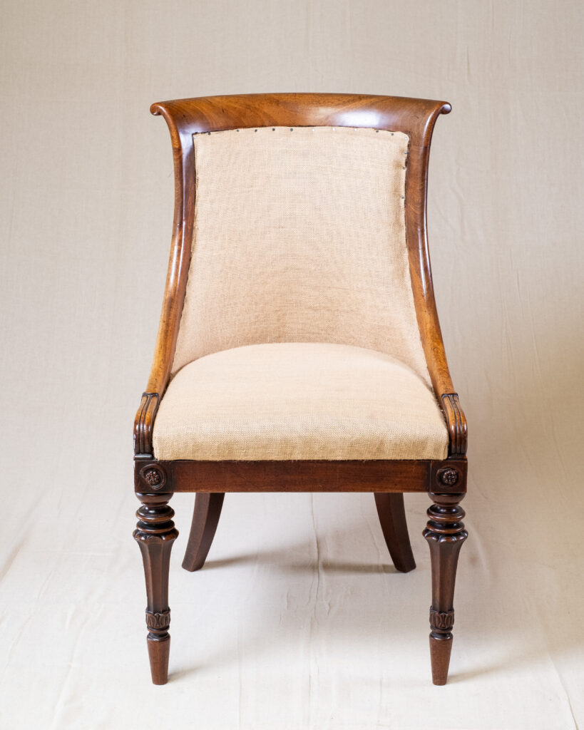 A carved mahogany chair with cream and red upholstery.