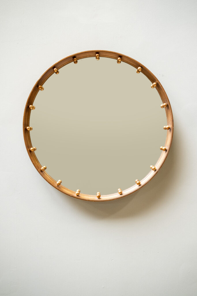 A circular mirror with a wooden frame and gilt studs.